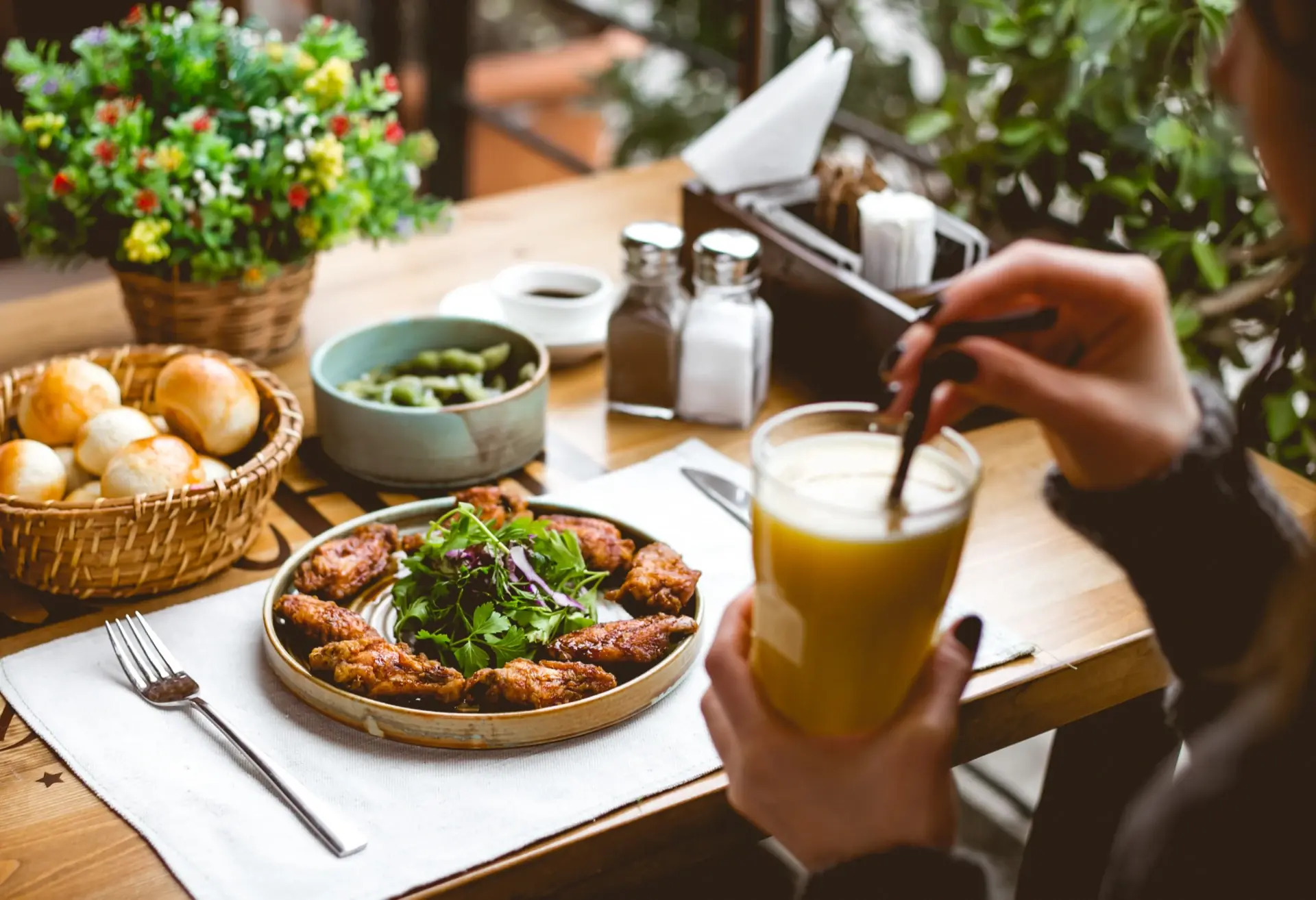 Mesa de restaurante servida com pratos e bebida, clima de salão cheio